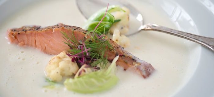 Heiß geräucherter Pfefferlachs serviert in Blumenkohlsuppe mit in Pfeffer gebratenen Blumenkohlröschen